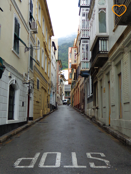 Foto de uma rua estreita. O rochedo aparece ao fundo.