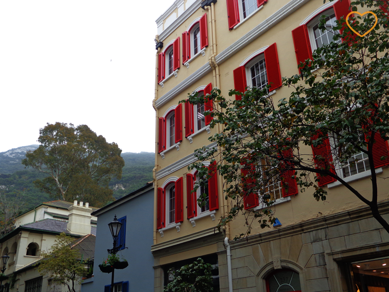 Foto de uma fachada de um edifício e umas casas e o rochedo ao longe.