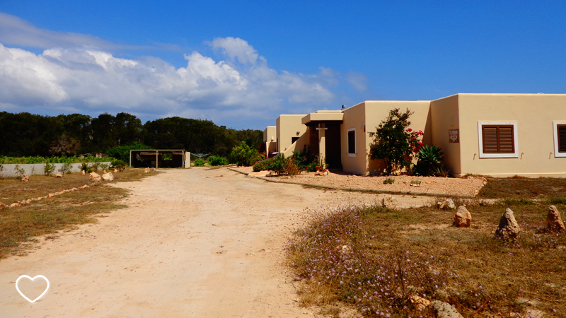 Estrada de terra e casas de arquitetura bem simples: praticamente cubos de cor bege.