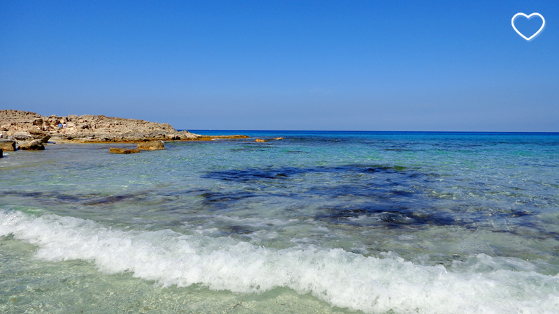 Praia de águas cristalinas e de diferentes tons de azul.