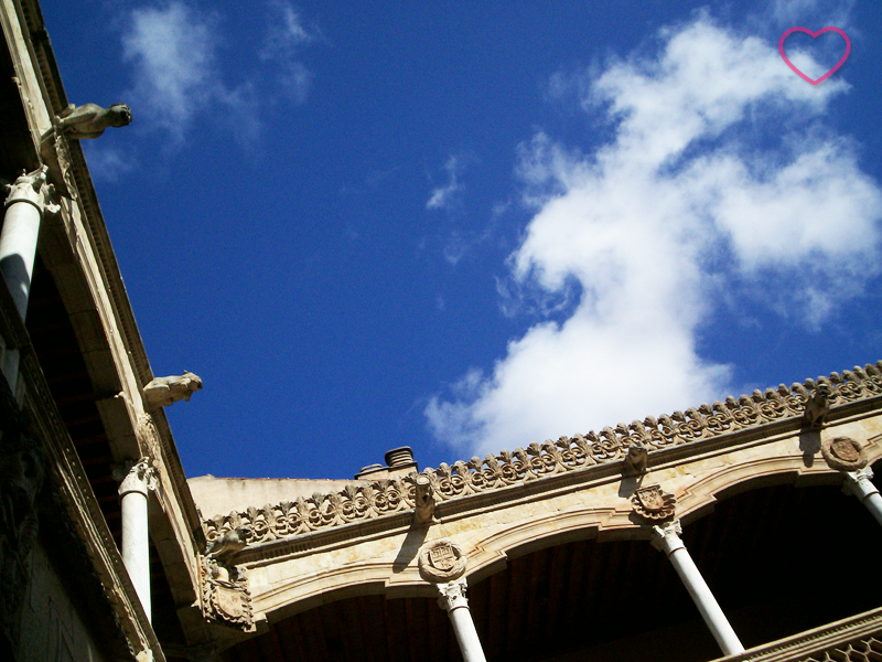 Céu azul e um enquadramento de baixo para cima do ângulo reto entre duas paredes de um pátio interno. Vê-se uma nuvem que eu acho que tem forma de burro.