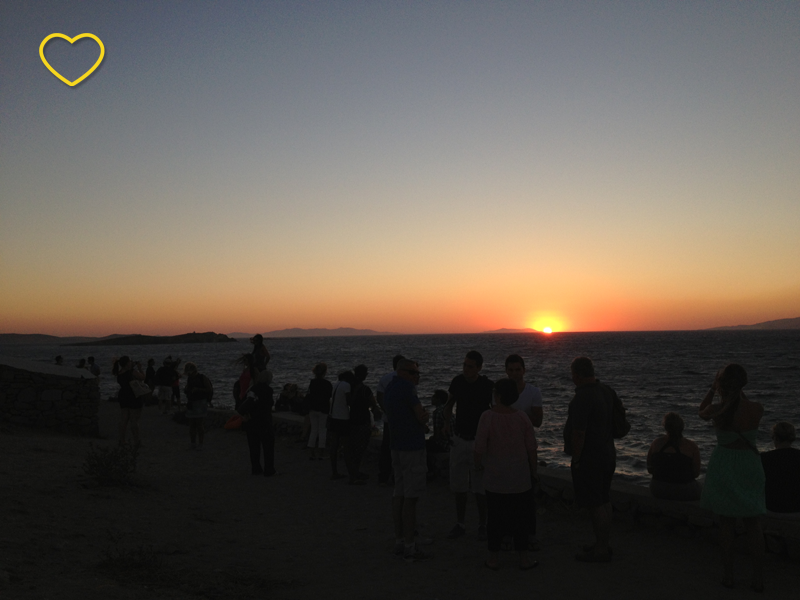 O pôr do sol e muitas pessoas assistindo.